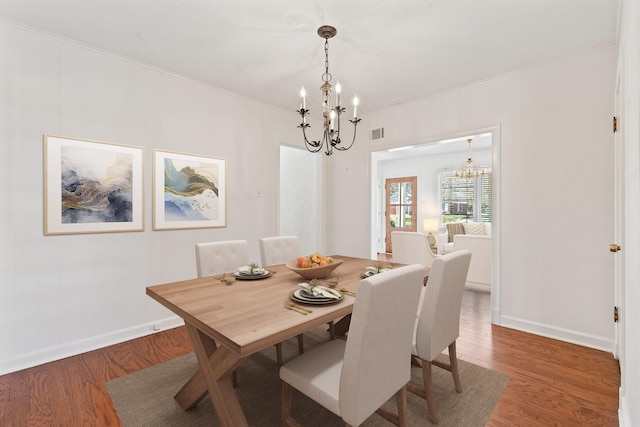 dining room with visible vents, an inviting chandelier, and wood finished floors