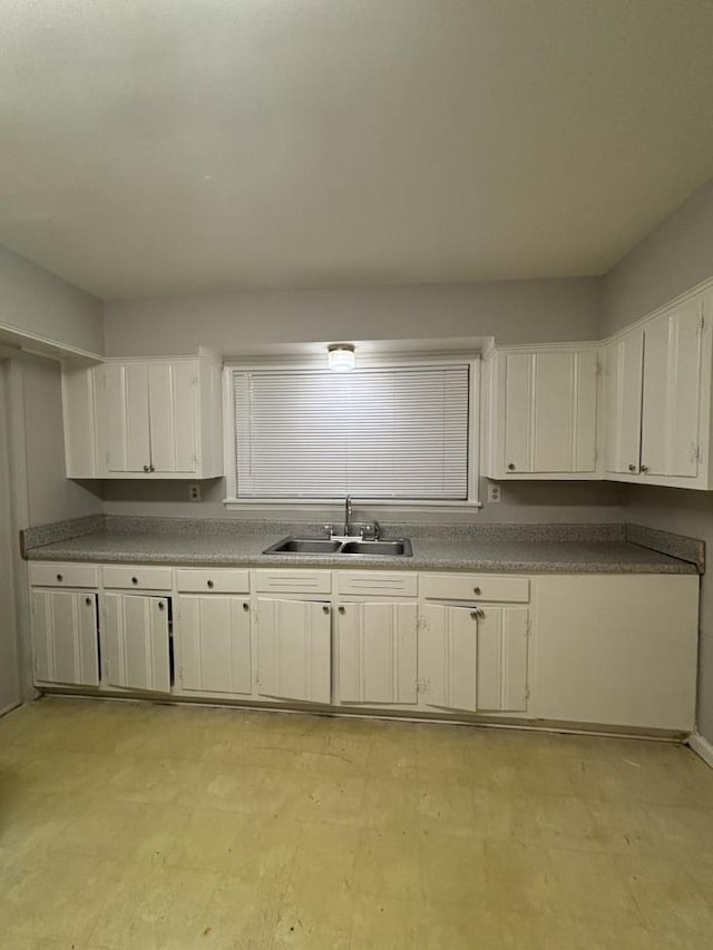 kitchen featuring light floors, white cabinetry, and a sink