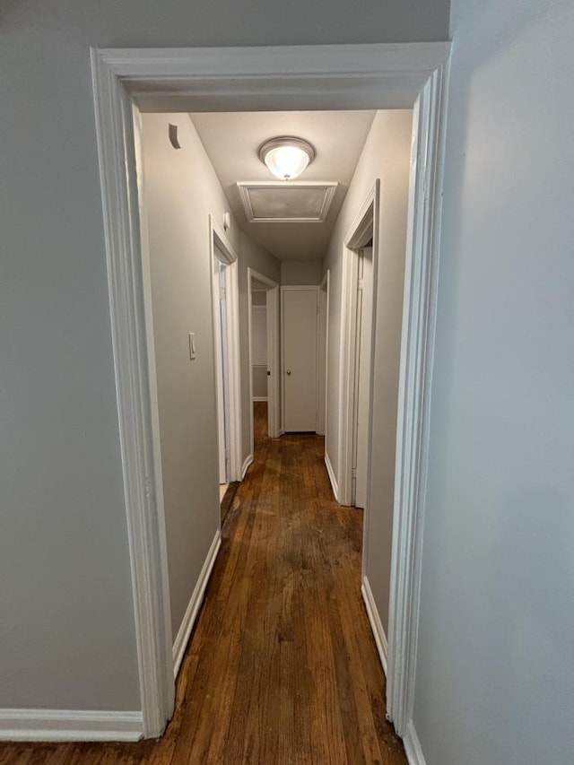 hallway with attic access, baseboards, and dark wood-style flooring