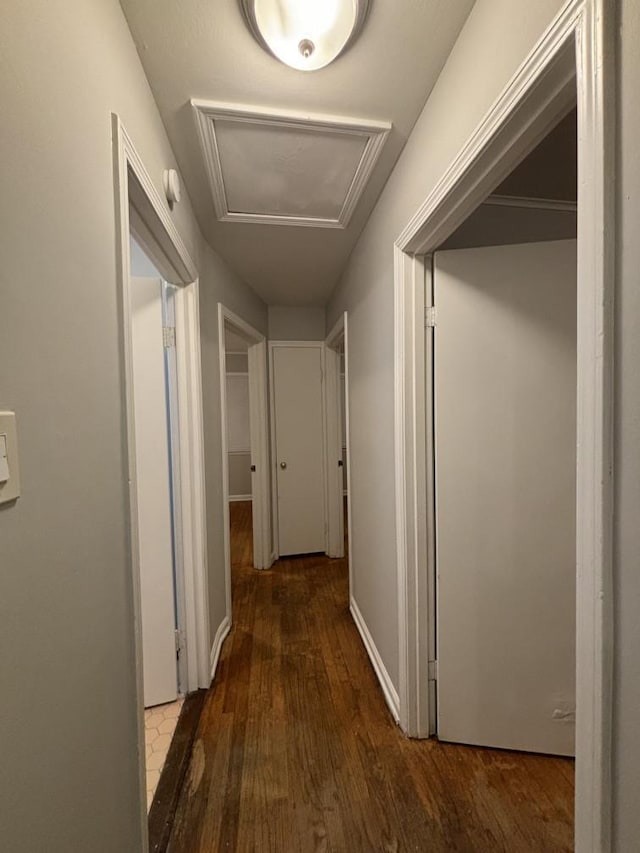 hall with attic access, baseboards, and wood finished floors