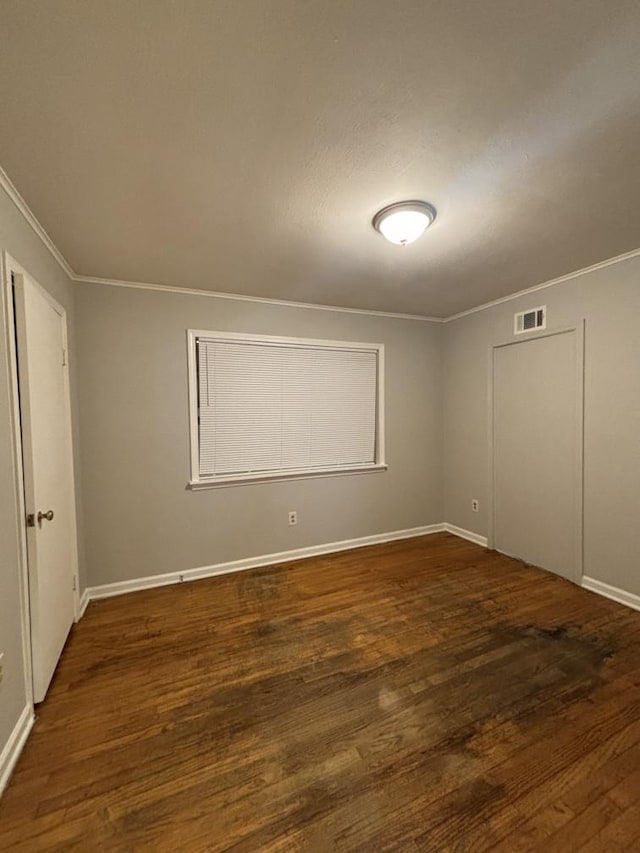 spare room with visible vents, crown molding, baseboards, and wood finished floors