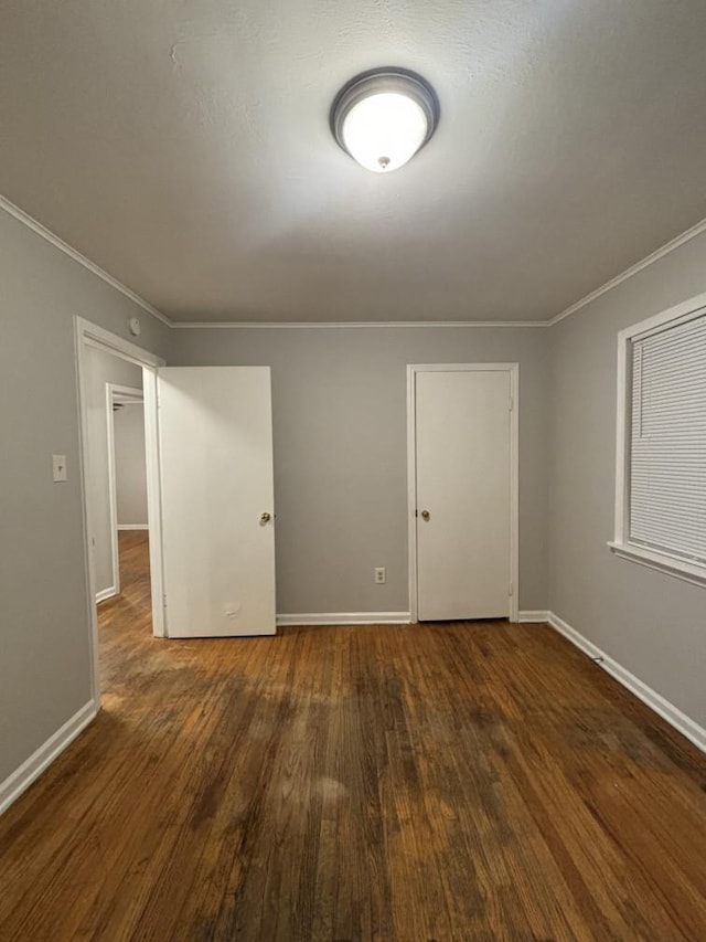 unfurnished room featuring baseboards, wood finished floors, and crown molding