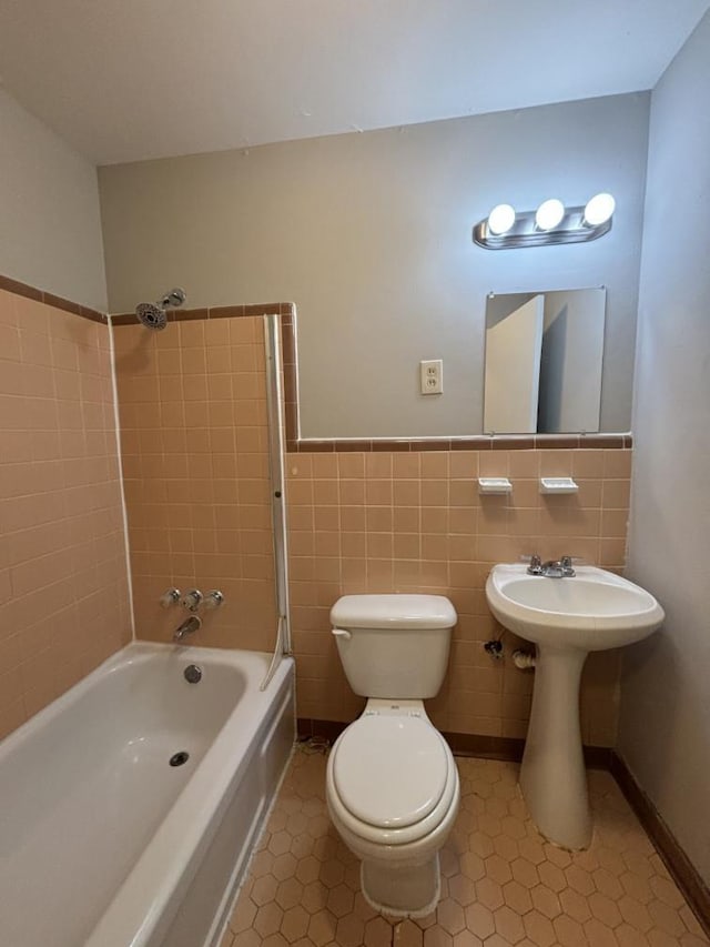 full bath featuring toilet, tile walls, wainscoting, and  shower combination