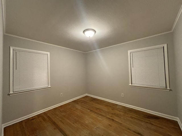 spare room with baseboards, ornamental molding, and dark wood-style flooring