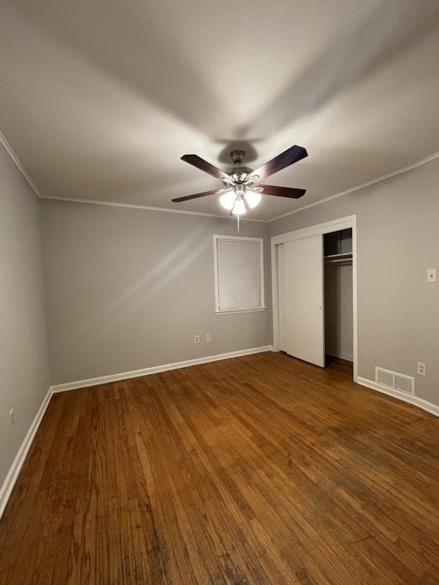 unfurnished bedroom featuring visible vents, ornamental molding, wood finished floors, a closet, and baseboards