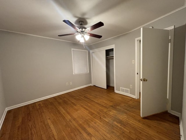 unfurnished bedroom with a closet, visible vents, crown molding, and wood finished floors