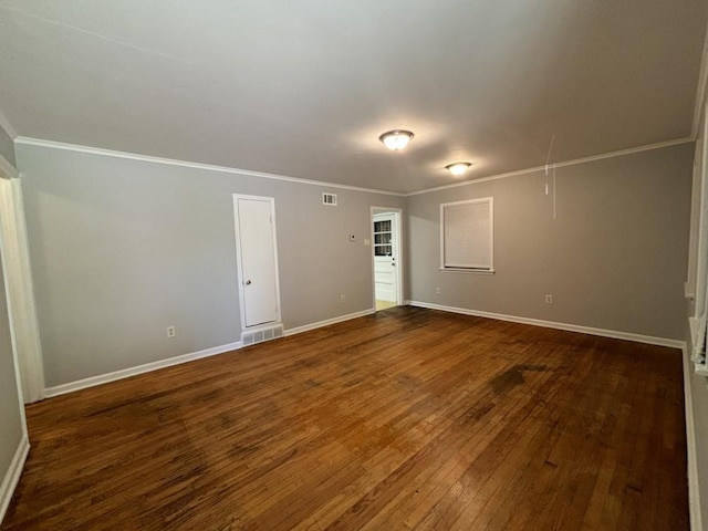 unfurnished room with dark wood-style floors, baseboards, visible vents, attic access, and ornamental molding