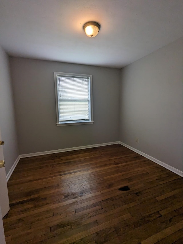 spare room featuring dark wood finished floors and baseboards