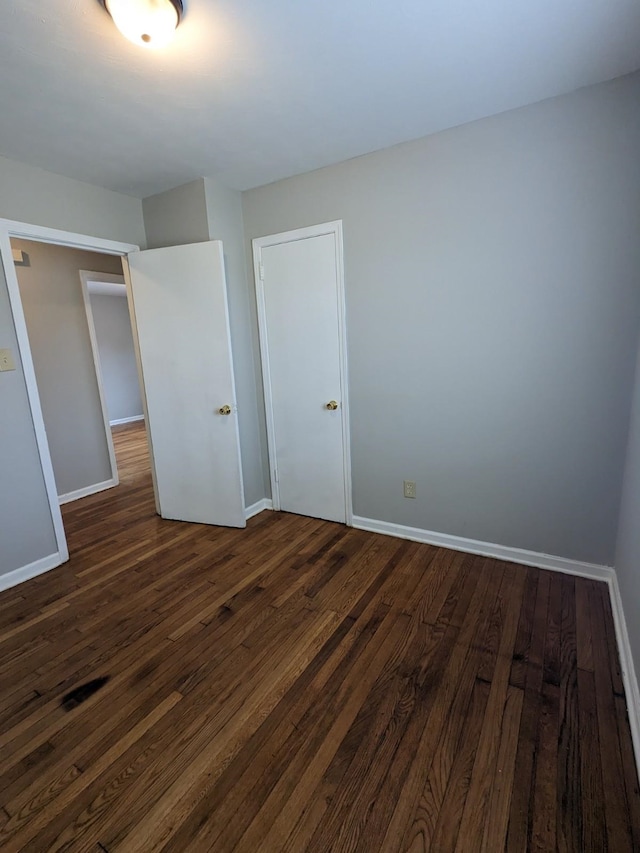 unfurnished bedroom featuring dark wood-style floors and baseboards