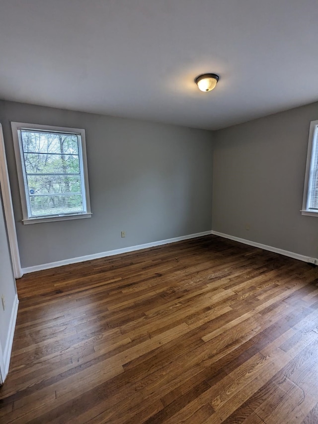 empty room with baseboards and dark wood-style floors