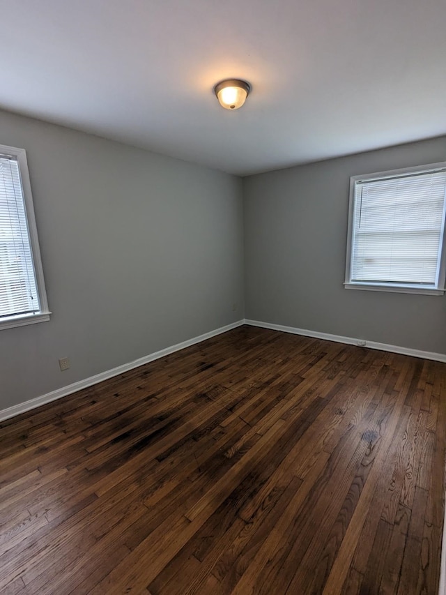 empty room with dark wood finished floors and baseboards