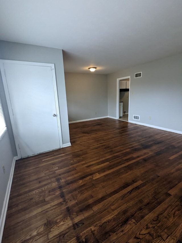 unfurnished room with visible vents, baseboards, and dark wood finished floors