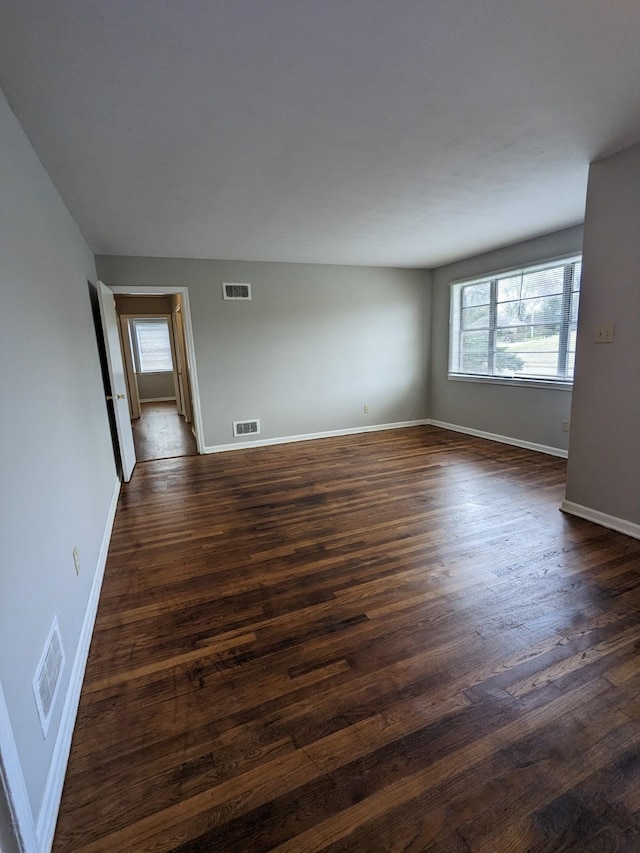 spare room with visible vents, baseboards, and dark wood-style flooring