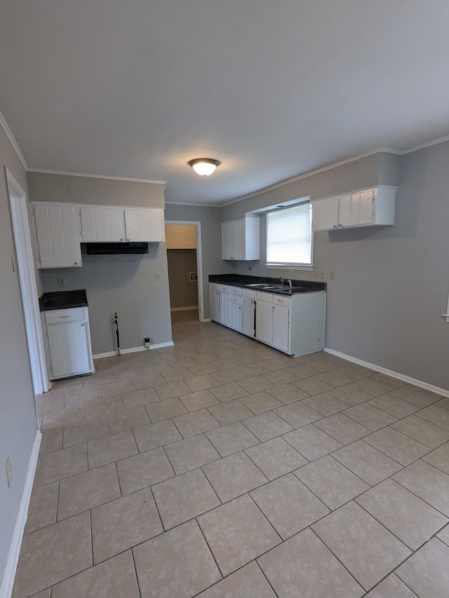 kitchen with crown molding, white cabinets, dark countertops, and baseboards