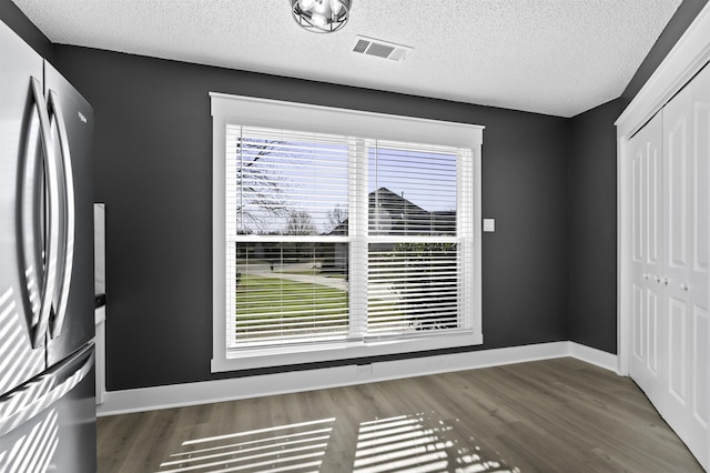 unfurnished bedroom with a closet, visible vents, wood finished floors, and freestanding refrigerator