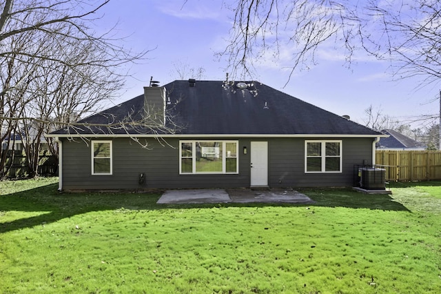 rear view of house with fence, a yard, a chimney, central air condition unit, and a patio area