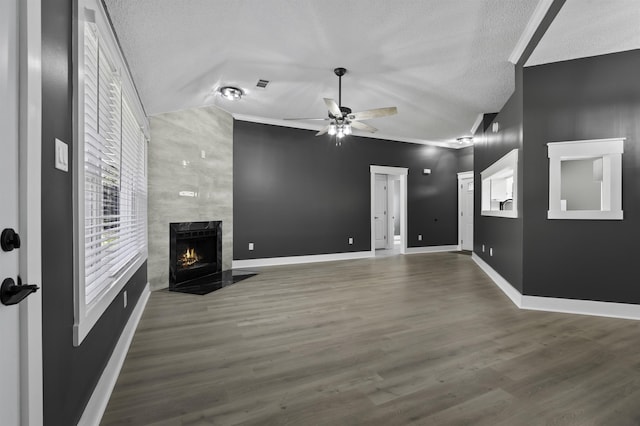 unfurnished living room featuring a ceiling fan, wood finished floors, lofted ceiling, a high end fireplace, and a textured ceiling