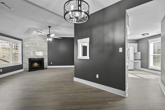 unfurnished living room with baseboards, visible vents, dark wood finished floors, a textured ceiling, and a large fireplace