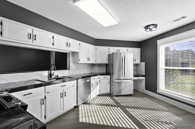 kitchen with a sink, visible vents, white cabinetry, and stainless steel appliances