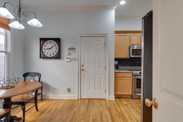 dining area with an inviting chandelier, light wood-type flooring, baseboards, and ornamental molding