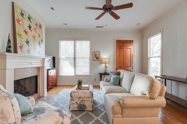 living room with visible vents, a healthy amount of sunlight, ornamental molding, and a tile fireplace