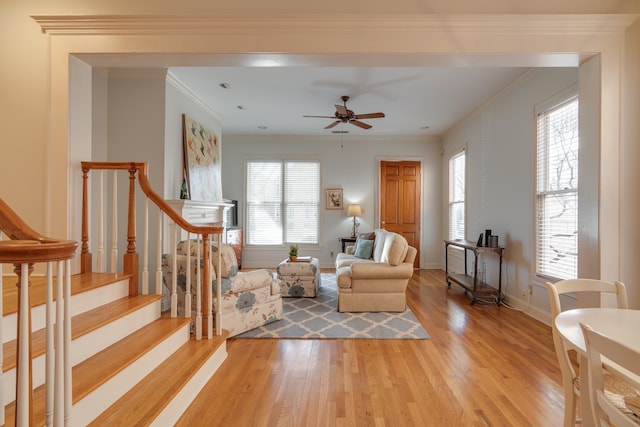 living room with stairway, light wood-type flooring, baseboards, and ornamental molding