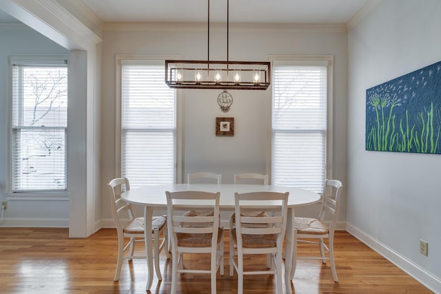 dining space featuring an inviting chandelier, baseboards, light wood finished floors, and ornamental molding