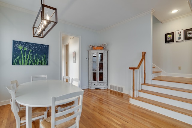 dining room with visible vents, light wood-style flooring, stairway, crown molding, and baseboards