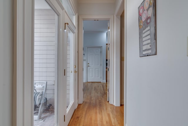 hall with light wood-type flooring and ornamental molding