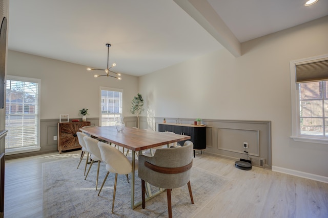 dining room with visible vents, light wood finished floors, beam ceiling, wainscoting, and a chandelier