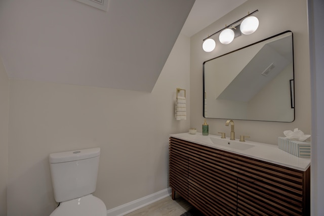 bathroom with visible vents, baseboards, toilet, vaulted ceiling, and vanity