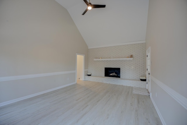 unfurnished living room with baseboards, light wood-type flooring, a fireplace, high vaulted ceiling, and a ceiling fan