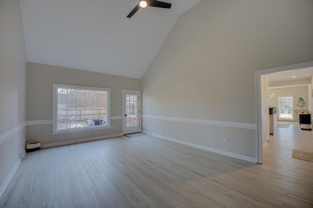 unfurnished room with a ceiling fan, wood finished floors, baseboards, and high vaulted ceiling