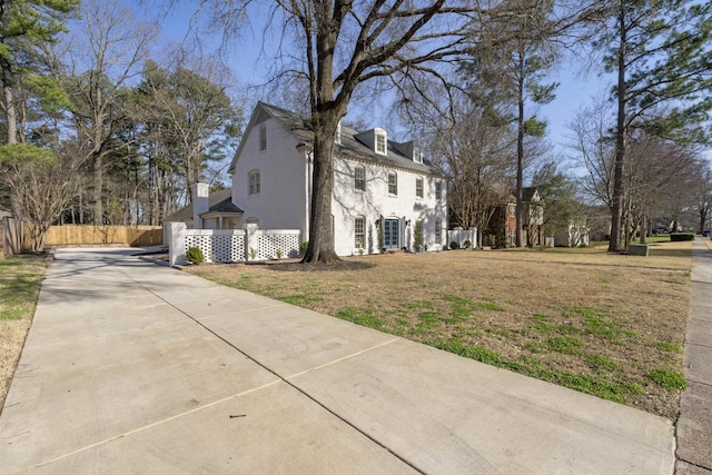 view of home's exterior with stucco siding, a lawn, concrete driveway, and fence