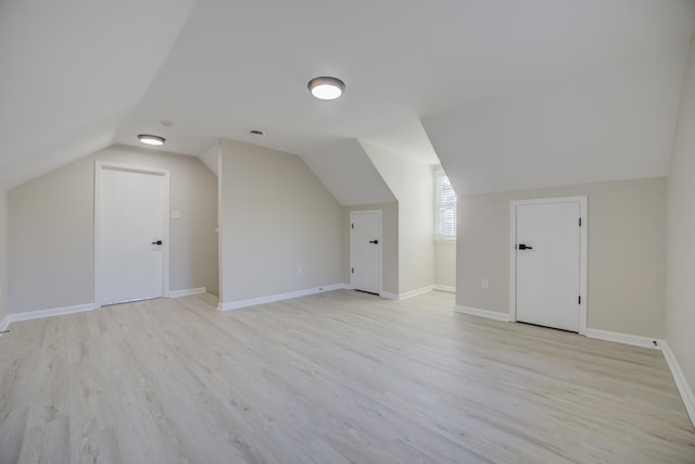 bonus room with baseboards, light wood-style floors, and vaulted ceiling