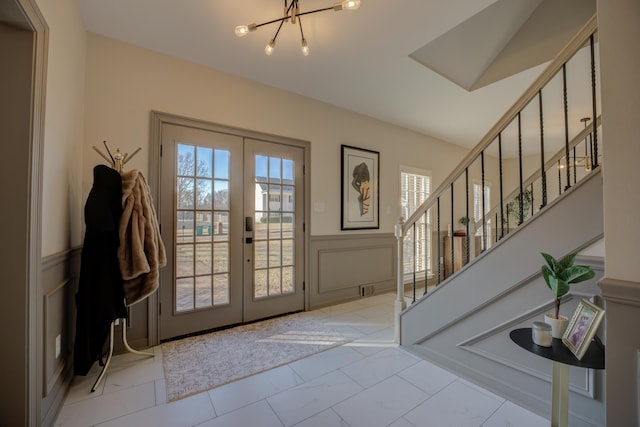 foyer featuring a wainscoted wall, stairway, marble finish floor, and a wealth of natural light