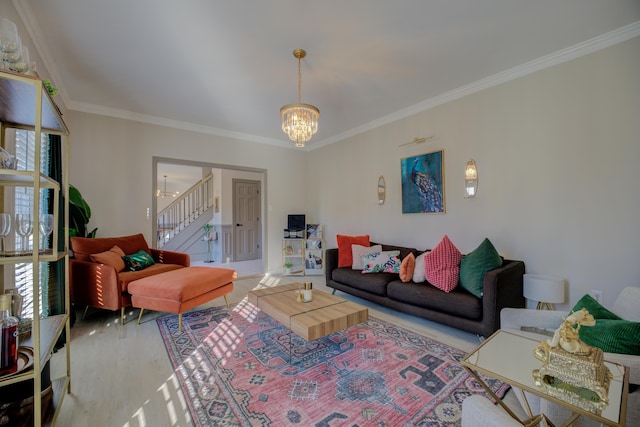 living room with stairway, a notable chandelier, crown molding, and light wood finished floors