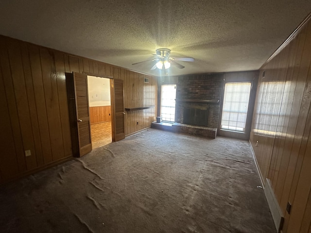 unfurnished living room with carpet, a healthy amount of sunlight, a fireplace, and a textured ceiling