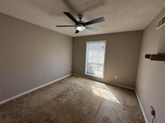 carpeted empty room with visible vents, ceiling fan, a textured ceiling, and baseboards