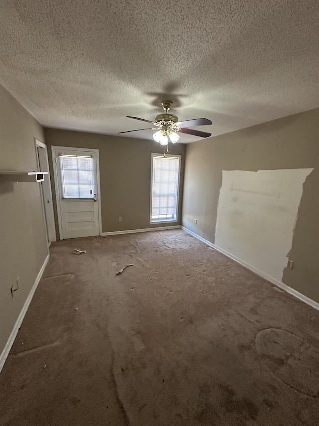 carpeted empty room with baseboards, a textured ceiling, and ceiling fan