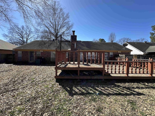 rear view of property featuring cooling unit, brick siding, a chimney, and fence