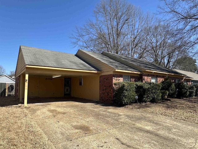 view of home's exterior featuring a carport, brick siding, and driveway