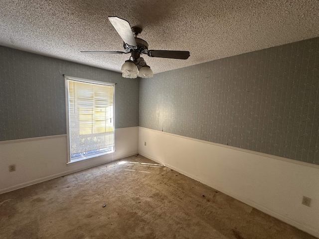 unfurnished room featuring a wainscoted wall, a textured ceiling, wallpapered walls, and carpet floors