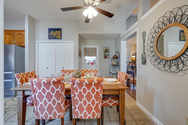 dining area with light tile patterned floors, a ceiling fan, and baseboards