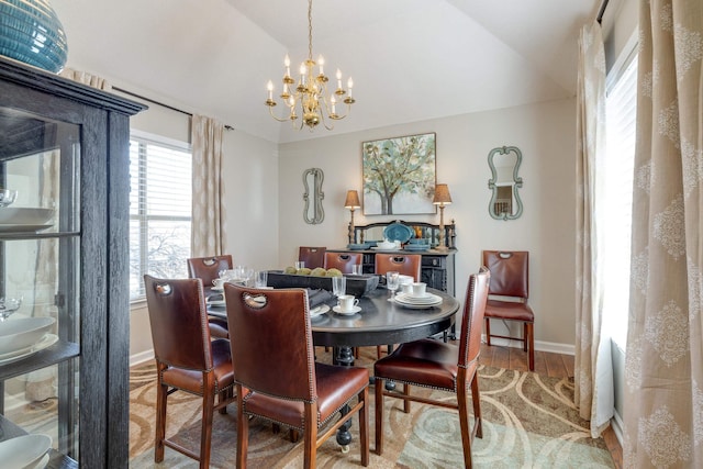 dining area featuring baseboards, wood finished floors, an inviting chandelier, and vaulted ceiling