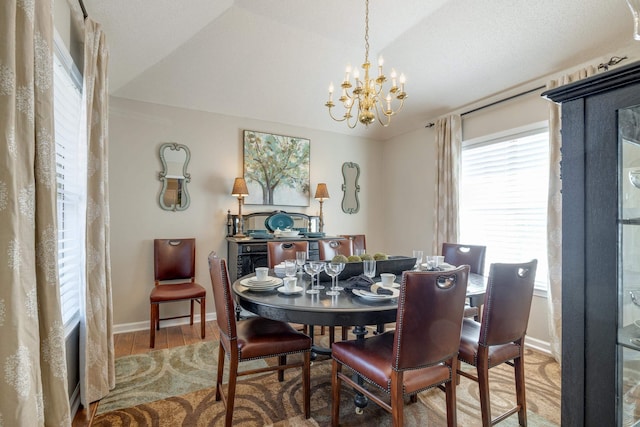 dining area featuring baseboards, lofted ceiling, an inviting chandelier, and wood finished floors