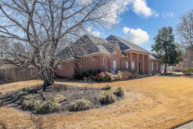 view of property exterior featuring a yard, brick siding, and fence