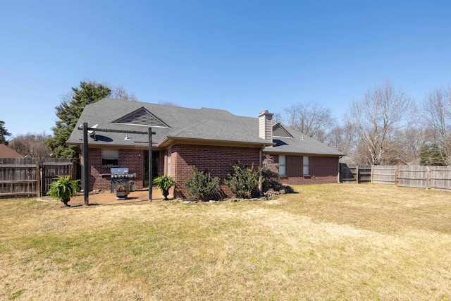 rear view of property with brick siding, a fenced backyard, a patio, and a yard