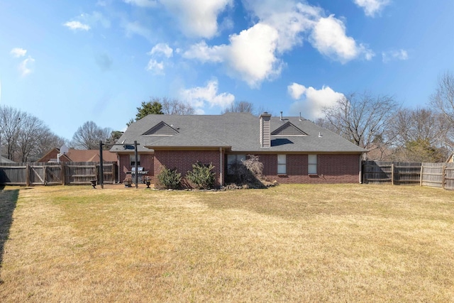 rear view of property featuring brick siding, a lawn, a chimney, a fenced backyard, and a gate