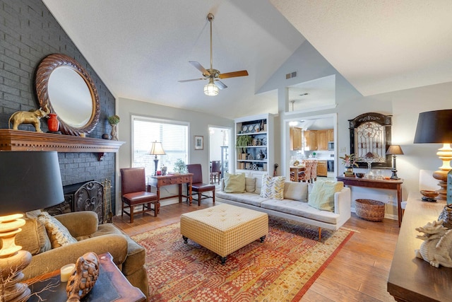 living area with visible vents, a fireplace, ceiling fan, and wood finished floors